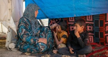 Shahinaz* and her grandsons sit in their tent at a camp  in north-west Syria following the 2023 earthquakes. Photo: Karam Al-Masri/Arete/DEC