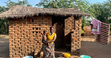 Eliza holds her baby outside her home in Bitilinyu camp