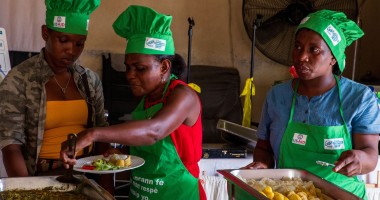 Three women in Concern chef hats cooking meal