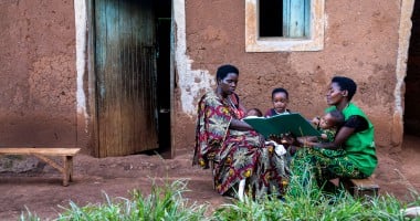 Two women and their children outside a house.