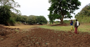 Two people stand next to a dry river bed