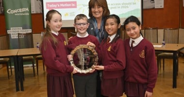 Students in red uniforms stand in Stormont holding awards