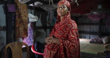 A pregnant woman in Bangladesh stands with her hands on her stomach
