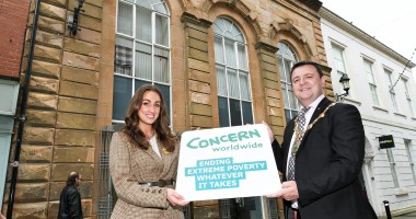 A woman and man holding a board outside an historic building
