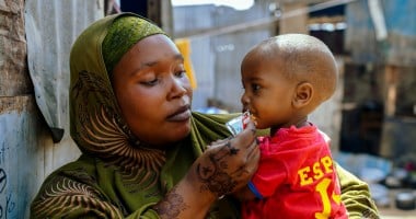 A woman in a displacement camp holding a young boy in her arms