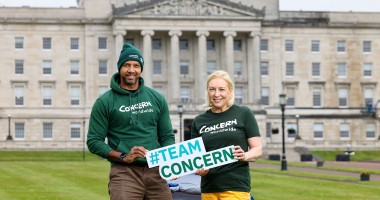 A man and woman holding a sign while standing outside Stormont in Belfast