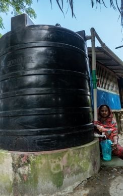 A water polymer tank preserving harvested rainwater in the backyard of Morium Begum’s house in Kalabogi, Sutarkhali, Dacope. Rainwater from her tin-shed roof is channelled to the tank through a water pipe where it is preserved for use throughout the year. Photo: Mumit M/Concern Worldwide