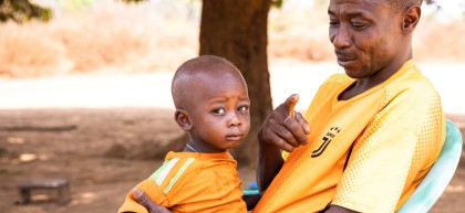 Alain* and baby Christian* in Ngata village outside their home on 22/02/22 Photo: Ed Ram/Concern Worldwide