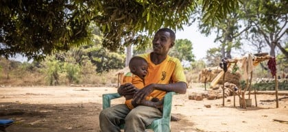 Alain* and baby Christian* in Ngata village outside their home on 22/02/22 Photo: Ed Ram/Concern Worldwide