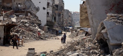 Shots of people walking passed destroyed buildings in Gaza, Oct 2024.