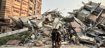 People stand past the debris of a collapsed building in Mandalay, Myanmar, on 28 March 2025 after the earthquake.