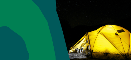 A glowing yellow tent illuminated from within stands in a dark campsite under a star-filled night sky. Hiking boots and trekking poles rest outside the entrance, suggesting a day of adventure.