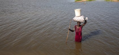 A woman in a red dress walks through flood water in South Sudan