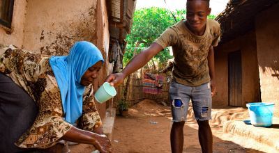 Marriam Jamali's son Bruno helps pour water on her hands while she washes them. They received soap as part of hygiene distribution to help prevent the spread of Covid-19 in Malawi.