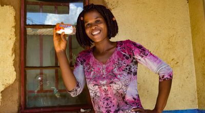 Smiling young woman Alice Eneya holds up soap she received from Concern.