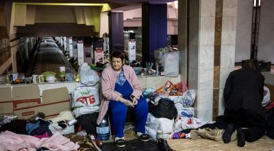 Woman looks sad sitting in Ukraine metro station surrounded by belongings