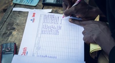 Hands writing details in a cash transfer notebook
