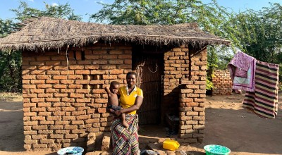 Eliza holds her baby outside her home in Bitilinyu camp
