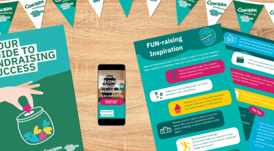 A flat lay image showing Concern Worldwide’s Ambassador fundraising resources: bunting with the Concern logo, a “Guide to Fundraising Success” booklet, a fundraising inspiration sheet with activity ideas, and a phone screen displaying the Concern Ambassador Programme for secondary schools.