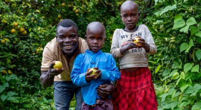 Father stands with two children on their farm, holding lemons