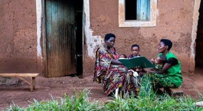 Two women and their children outside a house.