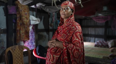 A pregnant woman in Bangladesh stands with her hands on her stomach