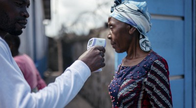 A staff member of the CBCA Virunga Hospital checks a visitor's temperature using a contactless infrared thermometer, before allowing her access to the hospital in Goma, DRC
