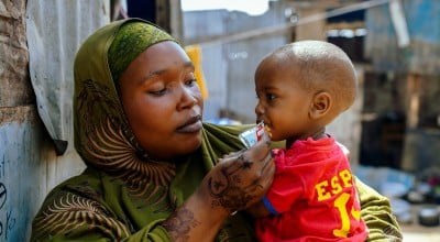 A woman in a displacement camp holding a young boy in her arms