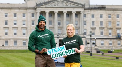 A man and woman holding a sign while standing outside Stormont in Belfast