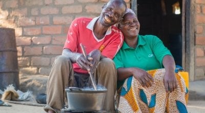 Chibala, 55, cooks at his home in May 2014 in Zambia with his wife Catherine, 43, sat next to him. Photo: Gareth Bentley / Concern Worldwide. 