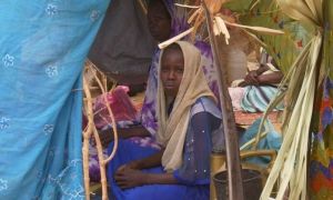 Sudanese refugee sits in makeshift tent in Chad