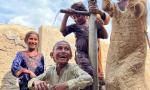 Children are bathing in the water of a village hand pump to cool down during the heatwave. Photo: Arif Shad/Concern Worldwide.