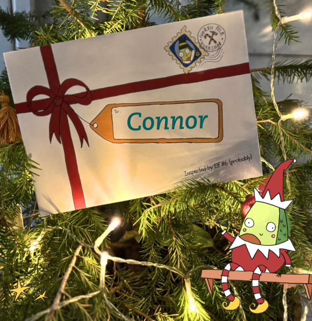 A personalised Santa Letter envelope labelled “Connor,” displayed on a Christmas tree with twinkling lights and an illustrated elf character.