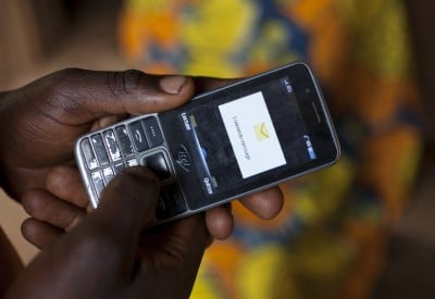 Olivier Irankunda (23) uses his mobile phone at his home in Mabayi, Cibitoke. Olivier is a beneficiary of the Graduation Programme and his business has gone from strength to strength. Photo: Abbie Trayler-Smith / Concern Worldwide