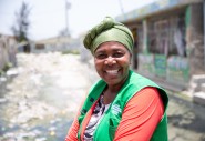 A smiling woman wears an orange top and a green Concern vest.