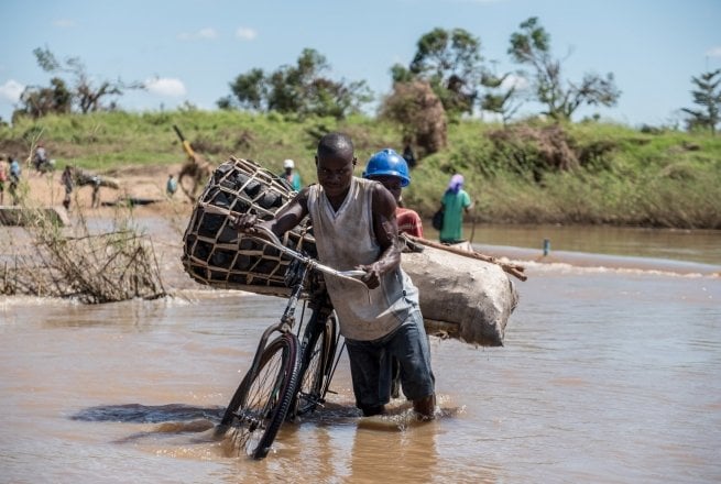 Zaccharia Roberto pushes his bicycle laden with charcoal across a flooded river near Nhamatanda, Mozambique. Cyclone Idai has disrupted infrastructure across the country, impacting livelihoods and hampering aid efforts. Photo: Tommy Trenchard / Concern Worldwide