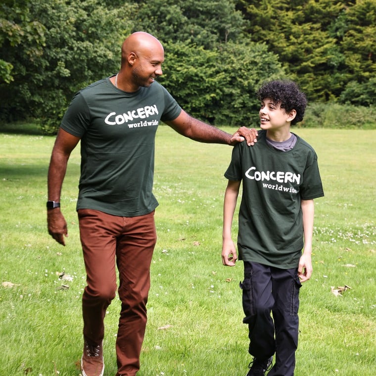 A man and boy take a walk surrounded by nature wearing Concern tshirts