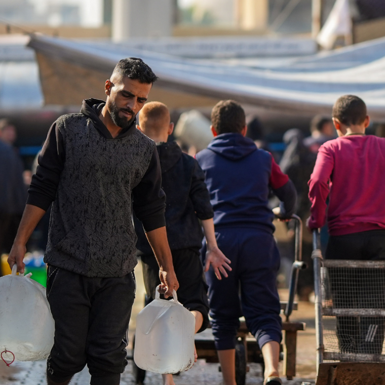 A man carrying water containers in a displacement camp